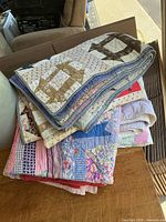Stack of three folded quilts showing varied fabrics and thickness