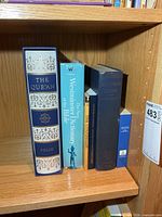 Shelf showing six religious texts including slipcased Qur'an and reference books