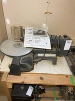 Scroll saw on bench with manual resting on table
