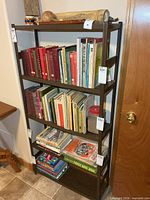 Full view of metal bookshelf with five shelves, books shown for scale