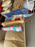 Rolled patchwork quilt wall hanging, tan rolled hanging, blue rolled scroll, colored glass pieces on couch