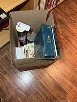 Box showing Trivial Pursuit box edge, cylindrical container, jar, loose game materials