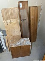 Boards, plywood sheets, wood prep box, small cabinet leaning against wall