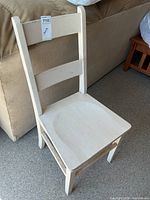 Front angled view of the wooden chair showing seat, legs and paint wear