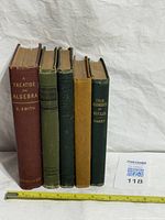 Front view of all five textbooks with measuring tape for scale