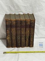 All six leather-bound volumes standing spine out showing gilt decoration and volume numbers