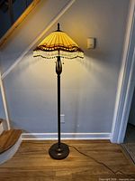 Full view of lamp showing stand, base, shade illuminated