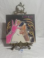 Front cover on display stand showing album art and title
