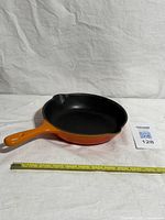 Full view of Le Creuset orange skillet with measuring tape for scale