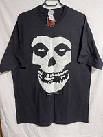 Front view of black Misfits T-shirt displaying large white skull graphic and tag attached