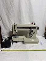 Front view of Kenmore 158 sewing machine with foot pedal and tape measure for scale