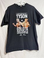 Full front view of black Tyson vs Golota event T-shirt on hanger