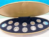 Open oval case displaying twelve encapsulated sterling-silver quarters