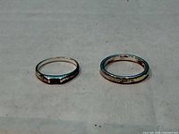 Two sterling silver rings side by side on surface