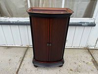 Front view of closed Bombay liquor cabinet showing slatted doors and bun feet