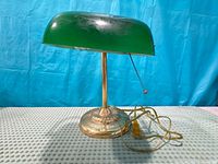 Front view of brass-tone desk lamp with green shade and cord visible