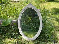 Front view of oval mirror showing frame, shell crest and glass