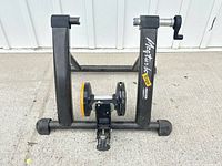 Front view of Minoura Magturbo Ergo trainer showing logo, resistance unit, frame, and axle mounts