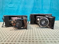 Front view of both folding cameras open showing lenses and bellows