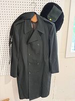 Full view of overcoat hanging with hat on pegboard