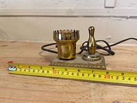Front view showing bowling pin finial, crown socket, measurement tape indicating width