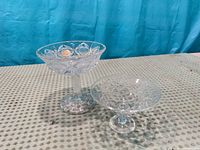two clear pressed glass pedestal bowls side by side