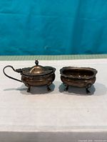Mustard pot with lid and open salt cellar side by side showing overall form and feet