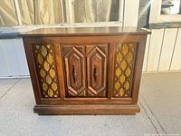 Front view of closed wood stereo cabinet showing decorative panels