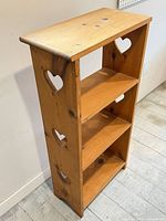 Front angled view of full shelf unit showing three shelves, heart cut-outs, overall condition