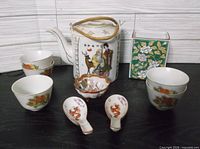 Group shot of teapot, cups, spoons, sauce dish, tea tin