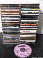 Full stack of approximately 50 CDs with one loose disc