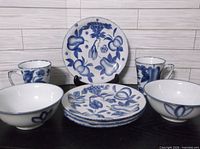 Group shot showing all dishware pieces: four plates, two bowls, two mugs