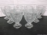 All eight clear fruit-embossed goblets grouped