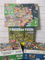 Stack of four boxed puzzles showing fronts and piece counts