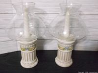 Pair of ceramic hurricane candle lamps with glass globes in full view