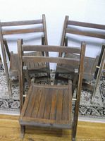 Group of three wooden folding chairs standing unfolded