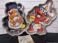 Both Wilton character cake pans side by side with instruction insert