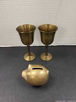 Two brass goblets and brass pig bank front view