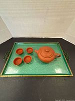Teapot with lid, four cups and green tray displayed together