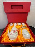 Red presentation box open showing entire 10-piece porcelain tea set