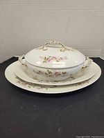 Covered casserole with lid atop two platters showing matching floral pattern