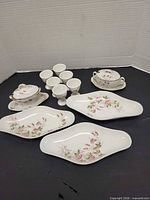 Group shot of all Limoges porcelain pieces: three oval dishes, six egg cups, two sugar bowls