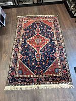 Full view of blue and red oriental-style area rug showing pattern, size and fringe