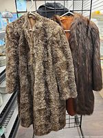 Front view of both fur coats hanging side by side on rack