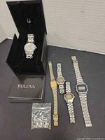 All five watches laid out with Bulova box, booklet and spare links