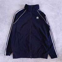 Front view of black Adidas SST windbreaker with white sleeve stripes and trefoil logo