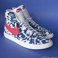 Side view of both sneakers showing tie-dye pattern, red swoosh, white midsoles