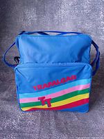 Front view showing rainbow stripe, Trafalgar text, TT logo, front zip pocket, overall colour and condition
