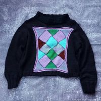 Front view of black oversized sweater with multicolor diamond patchwork