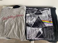 Folded view showing gray Rolling Stones tee and black Pink Floyd tee side by side